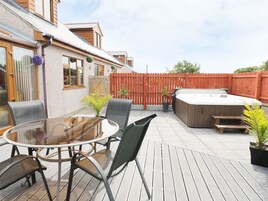 Un patio con una mesa redonda y sillas, un jacuzzi y una terraza de madera.