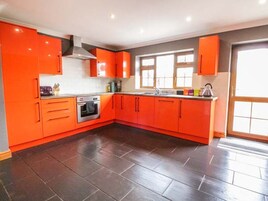 Una cocina con gabinetes color naranja, un horno de acero inoxidable y una ventana.