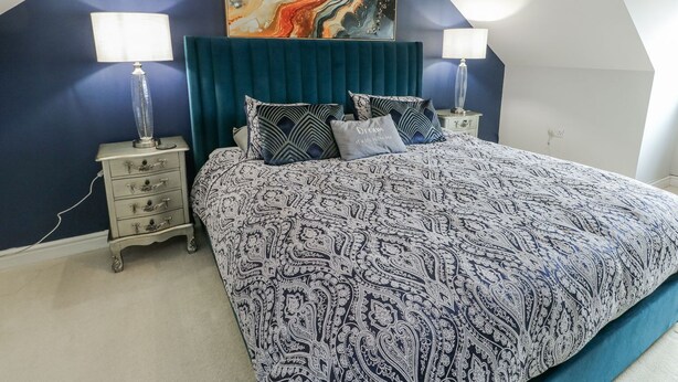 A bedroom with a large bed, two bedside tables, a headboard, and a wall painting. - 1 The Old Smithy (Cemaes Bay)