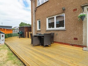 A wooden deck with outdoor furniture, a brick house, and a small shed. - 6 Niddrie Marischal Road (Edinburgh)