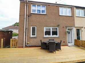 A two-story house with a patio area featuring a table and chairs. - 6 Niddrie Marischal Road (Edinburgh)