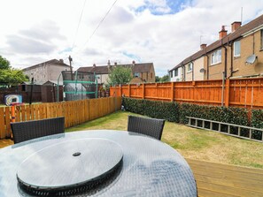 A circular outdoor table with chairs, a wooden fence, and a hedge in a residential backyard. - 6 Niddrie Marischal Road (Edinburgh)