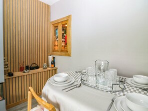 A dining area with a checkered tablecloth, white plates, and clear glassware. - 6 Niddrie Marischal Road (Edinburgh)