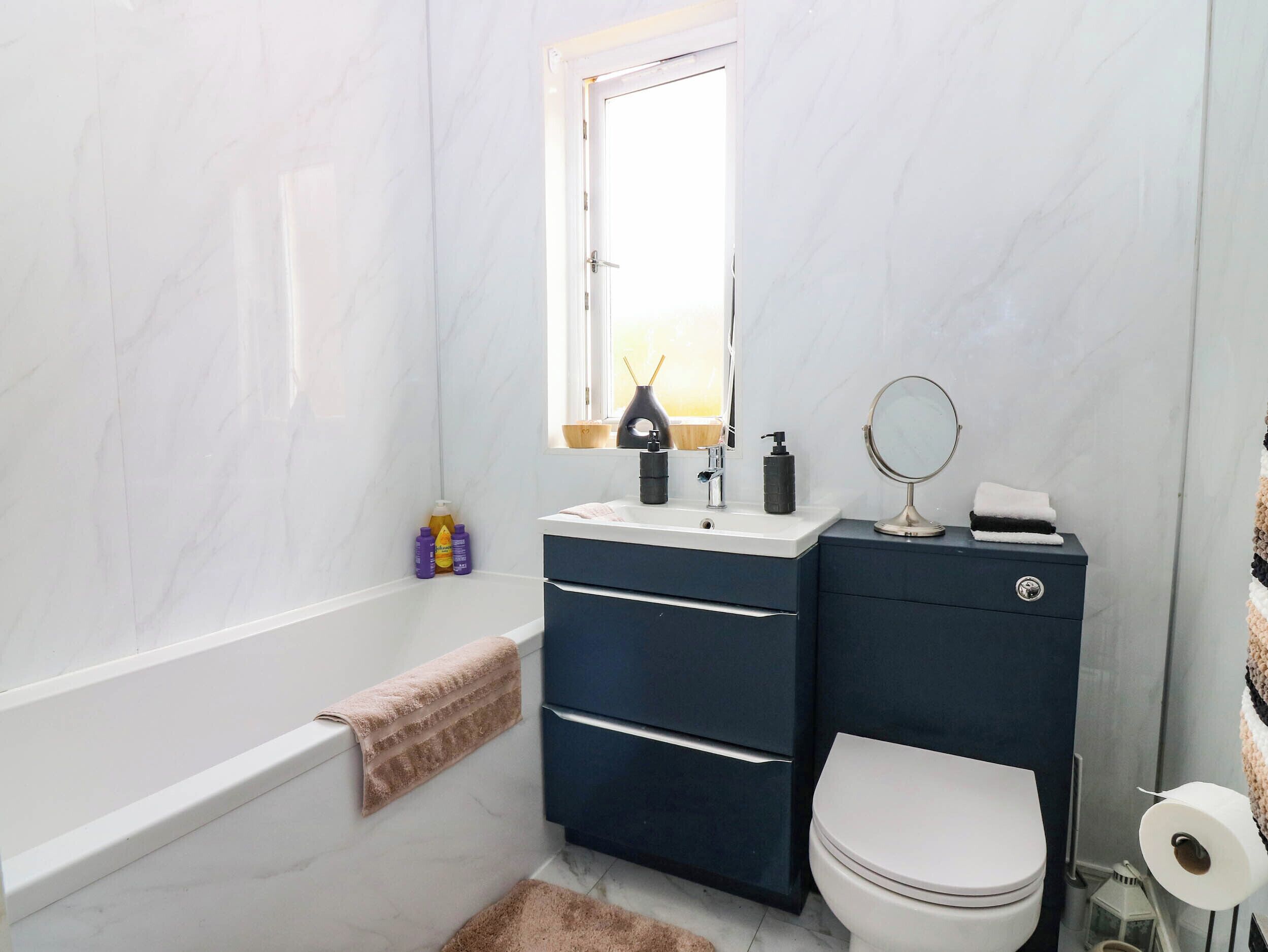 A bathroom with a bathtub, a toilet, a sink with a mirror, and toiletries.