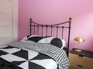 A bed with a black and white checkered bedspread, a metal headboard, and a bedside table with a lamp. - 6 Niddrie Marischal Road (Edinburgh)