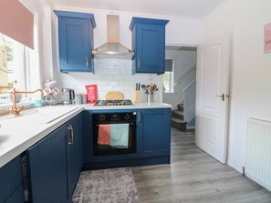 A kitchen with blue cabinets, a stove, and a dishwasher. - 6 Niddrie Marischal Road (Edinburgh)