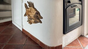 Une cuisine équipée d’un four encastré, avec une horloge au mur et un objet décoratif en bois posé sur le plan de travail.