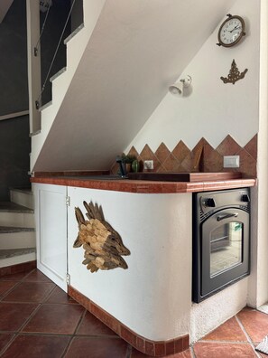 Eine Küche mit Einbauofen, einer Wanduhr und einem dekorativen Holzobjekt auf der Arbeitsfläche.