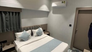 Une chambre d’hôtel avec un lit, une table de chevet et un luminaire au plafond.