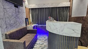Un espace d’accueil moderne avec un sol en marbre, un comptoir d’accueil incurvé et un coin salon avec un canapé.