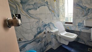 Une salle de bain avec un mur décoré de motifs en marbre, des toilettes, un lavabo et une douche.