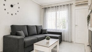 A living room with a grey sofa, a white coffee table, and a wall clock. - Pet friendly home in Torrevieja with WiFi (Torrevieja)