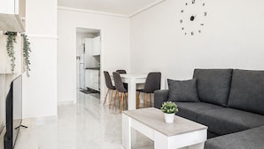 A modern living room with a grey sofa, a white coffee table, and a dining area with chairs and a table. - Pet friendly home in Torrevieja with WiFi (Torrevieja)