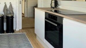 A modern kitchen with white cabinetry, a stainless steel kettle, and a built-in oven. - Panoramic view over Storebælt from Drøsselbjerg (Slagelse)