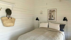 A bedroom with a bed, two bedside lamps, a wall-mounted basket, and a framed picture. - Panoramic view over Storebælt from Drøsselbjerg (Slagelse)