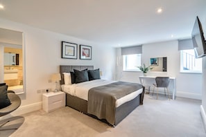 Een moderne slaapkamer met een groot bed, nachtkastjes, een bureau en een stoel.