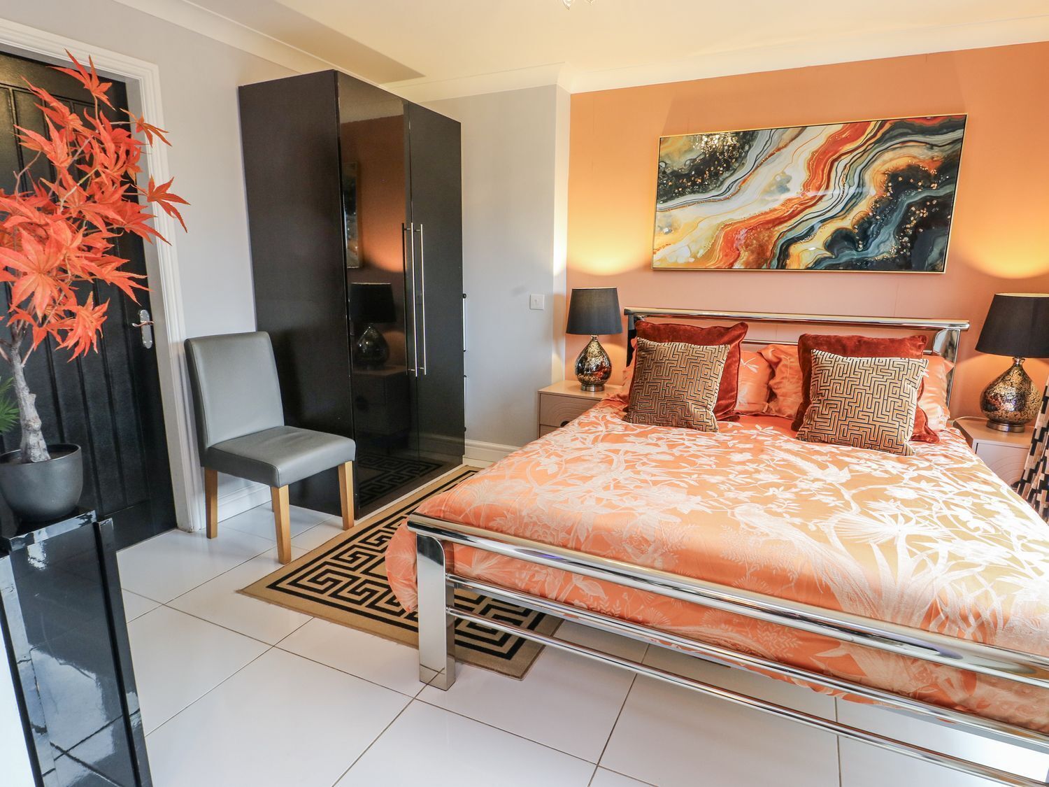 Un dormitorio moderno con una cama grande, una silla, una planta en maceta y un cuadro en la pared.