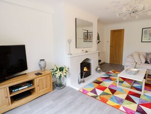 Una sala de estar con chimenea, televisor, sofá y un tapete colorido.