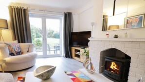 Una sala de estar con chimenea, un sofá, una televisión y un ventanal grande.