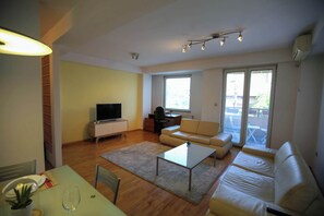 Un salon comprenant un canapé, une table basse, un téléviseur et un coin repas avec une table et des chaises.