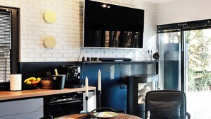 Una cocina moderna con comedor, que incluye una mesa redonda de madera, sillas negras y un televisor integrado sobre la encimera.