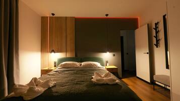 Una camera d'albergo moderna con un letto grande, lampade sui comodini, un armadio in legno e vista sul corridoio.