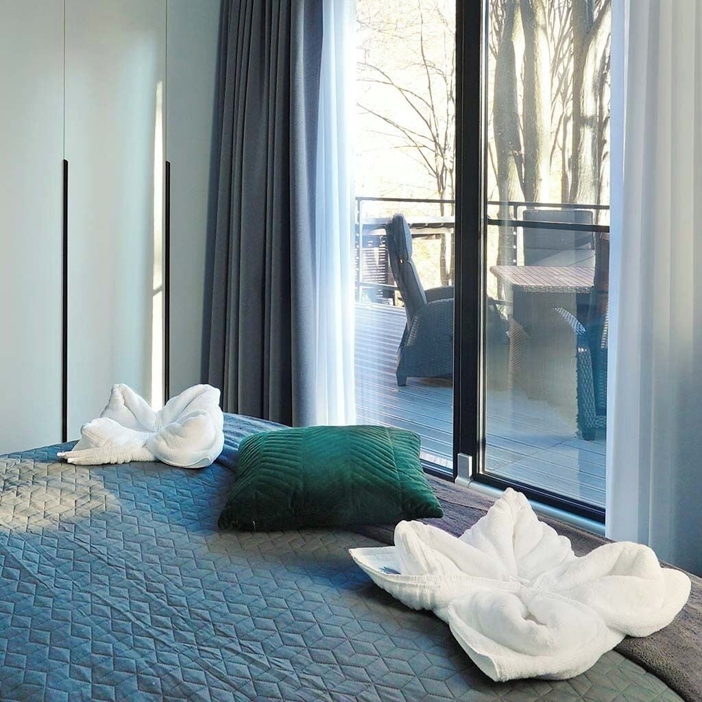 A hotel room with a bed, a green pillow, and a white towel.