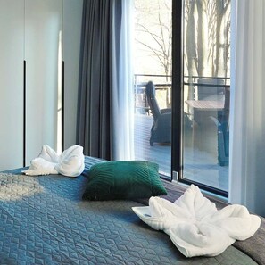 A hotel room with a bed, a green pillow, and a white towel.