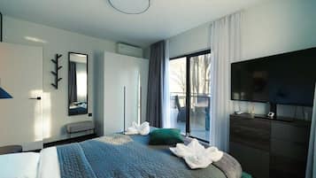 Une chambre d’hôtel moderne dotée d’un grand lit, d’un téléviseur à écran plat et d’une porte-fenêtre coulissante donnant sur l’extérieur.