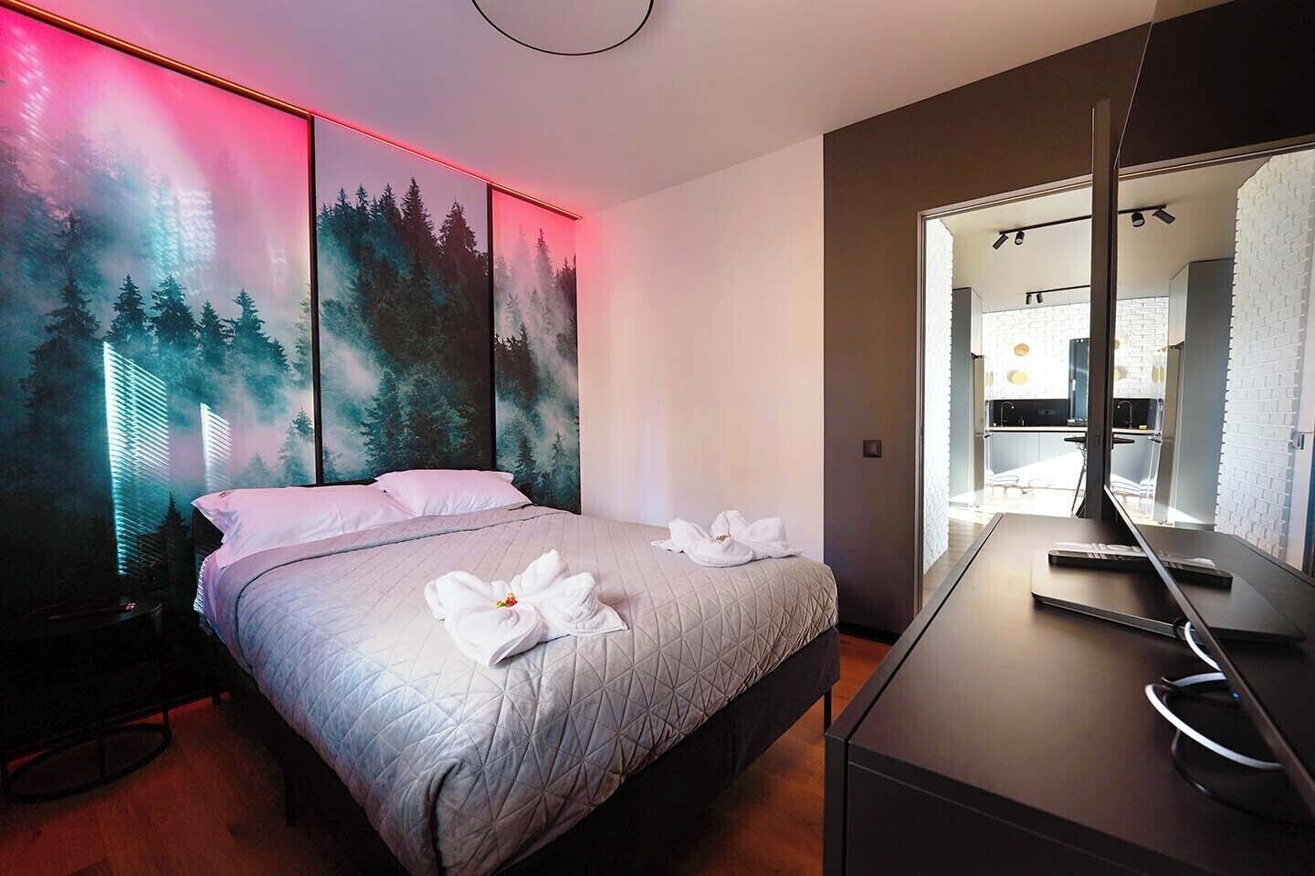 Een moderne hotelkamer met een bed, een bureau en een grote spiegel.