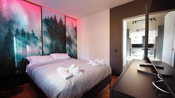 Een moderne hotelkamer met een bed, een bureau en een grote spiegel.
