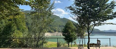 A deck with sun loungers overlooking a lake and mountains.