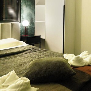 A hotel room with a bed, bedside table, lamp, and a wardrobe.