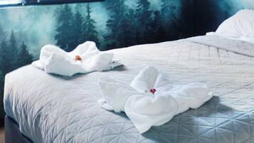 Una cama con una colcha acolchada y dos toallas blancas con forma de cisnes adornadas con flores rojas.