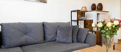 A modern living room with a grey sectional sofa, a wooden coffee table, and a vase with flowers.