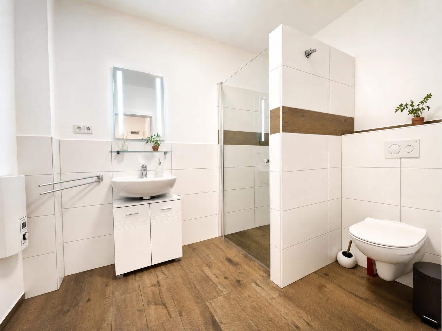 Ein modernes Badezimmer mit Waschbecken, Spiegel, Dusche und Toilette.