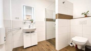 Ein modernes Badezimmer mit Waschbecken, Spiegel, Dusche und Toilette.