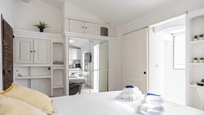Ein Hotelzimmer mit Bett, Schreibtisch, Stuhl, einer kleinen Küchenzeile und einem Badezimmer.
