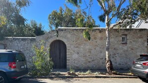 Un bâtiment en pierre avec une grande porte en bois, des voitures garées et des arbres.