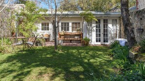 Une maison avec un porche à l’avant, un petit jardin et un banc en bois.