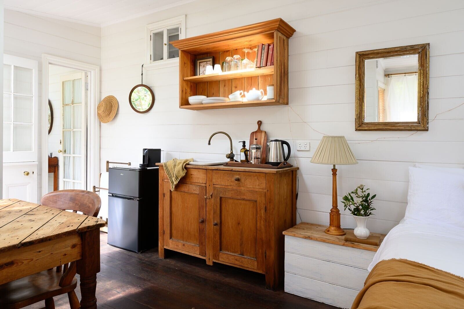 A compact kitchen with wooden cabinets, a sink, a refrigerator, and a dining area with a table and chairs.
