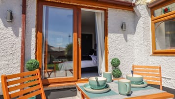 Une terrasse avec une table dressée pour deux personnes, une chaise en bois et une petite plante en pot.