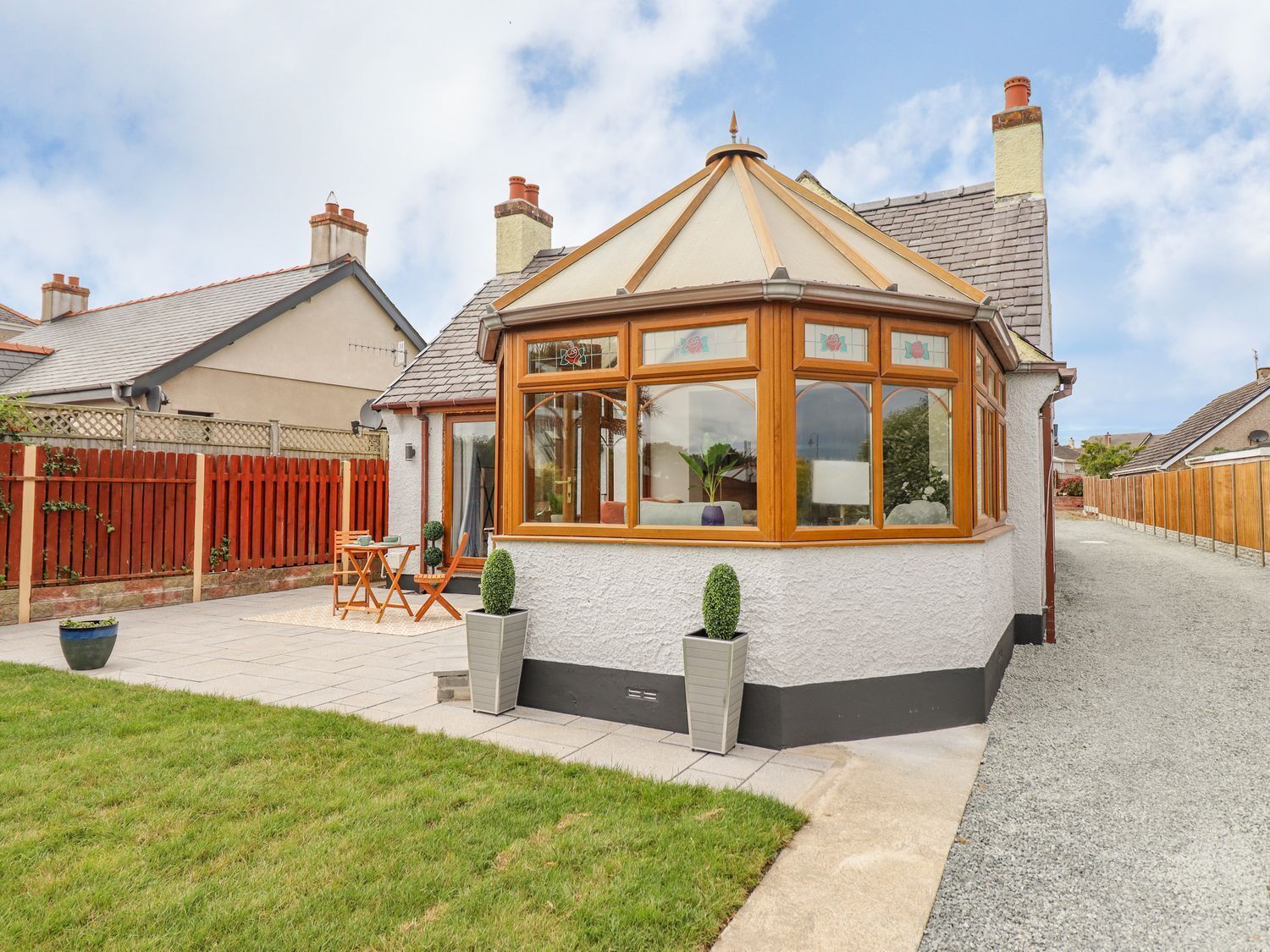 A conservatory with a tiled roof, a wooden door, and a small patio area with a table and chairs.