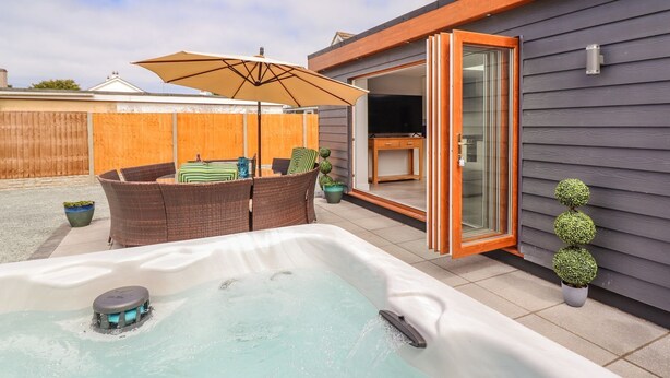 Ein Garten mit Whirlpool, Gartenmöbeln und einer Holzterrasse.