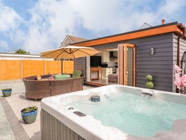 Patio trasero con jacuzzi, mobiliario exterior y puerta corrediza de vidrio que da a una cocina.
