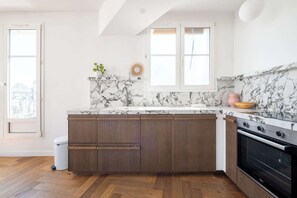 Eine Küche mit Marmorarbeitsplatte, Holzschränken und einem eingebauten Backofen.