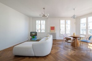 A modern living room with a sofa, chairs, a dining table, and a radiator. - Bright and Spacious 1BDR in Central Paris (Paris)