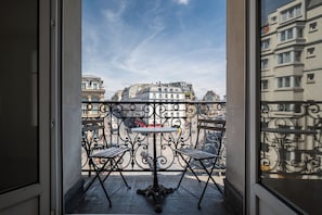 A balcony with wrought iron railings, two wooden chairs, and a small round table. - Bright and Spacious 1BDR in Central Paris (Paris)