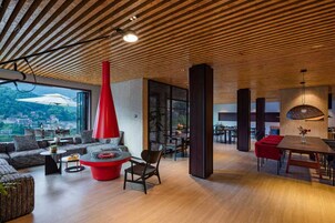 A spacious interior with a high ceiling, a dining area, and a seating area with a red accent piece.
