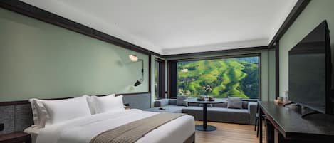 Et moderne hotelværelse med en stor seng, en sofa, et spisebord og et fjernsyn.